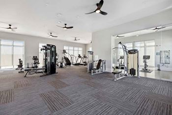 A spacious gym with a variety of equipment and a ceiling fan.
